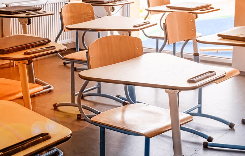 Series of modern wooden desks in an empty classroom