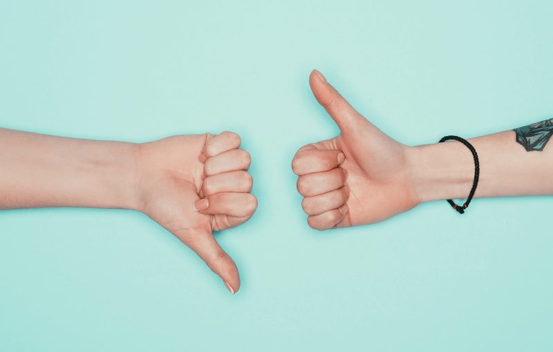 Two hands on a blue background, one gives the "thumbs up" and the other "thumbs down"