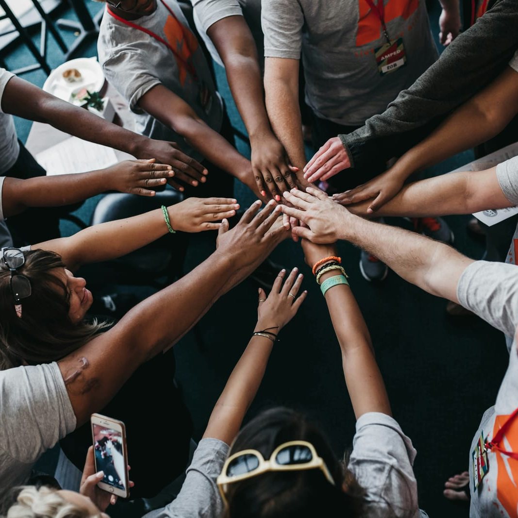 A team in matching T-shirts joins hands in a circle.