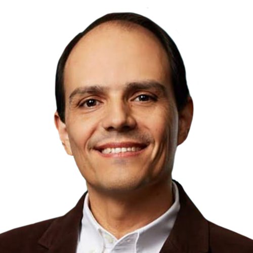Roberto Gálvez, smiling, with short dark hair, in a dark blazer over a white shirt